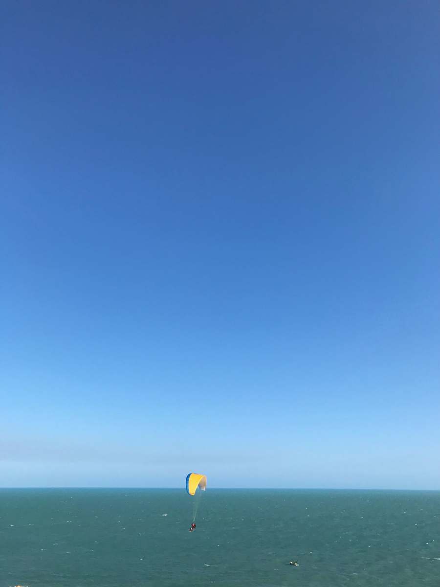 leisure activities person paragliding above blue sea during daytime gliding